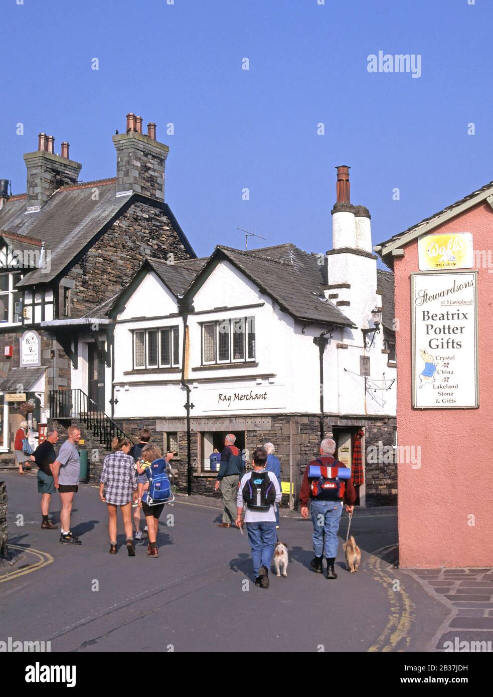 Ambleside Lake District Dorf Hundewiesen Paar & Rucksack Touristen neben Beatrix Potter Gift Shop anmelden Menschen in engen Straße Cumbria England Großbritannien Stockfoto