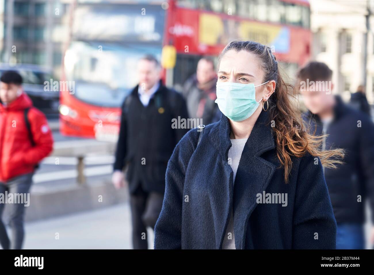 Junge Frau, die Gesichtsmaske trägt, während sie in den Straßen Londons spazieren ging Stockfoto