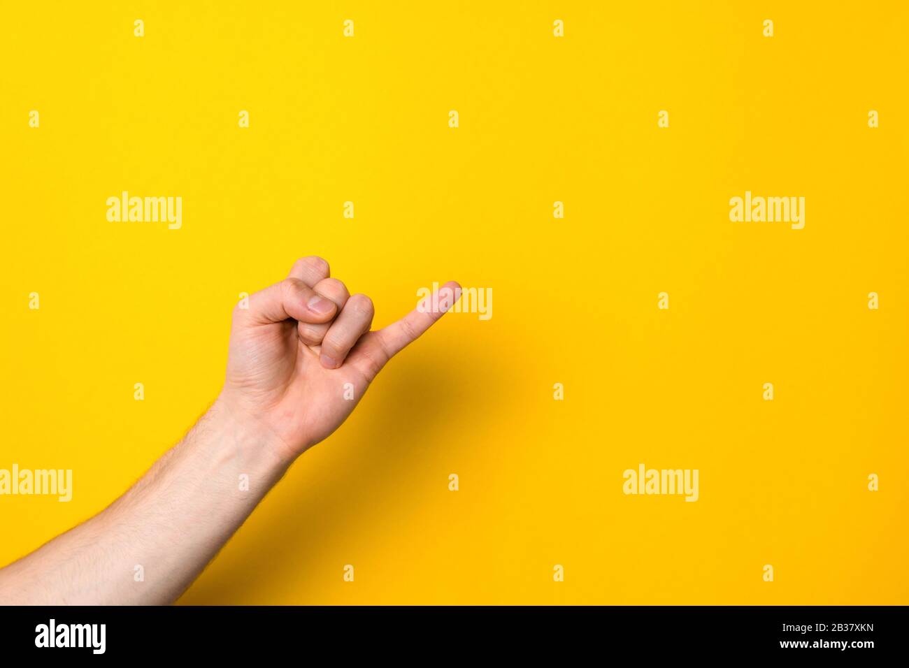 Pinkie. Halten des Versprechungszeichens. Kleiner Finger der männlichen Hand vor gelbem Hintergrund mit Kopierraum für Werbung Stockfoto