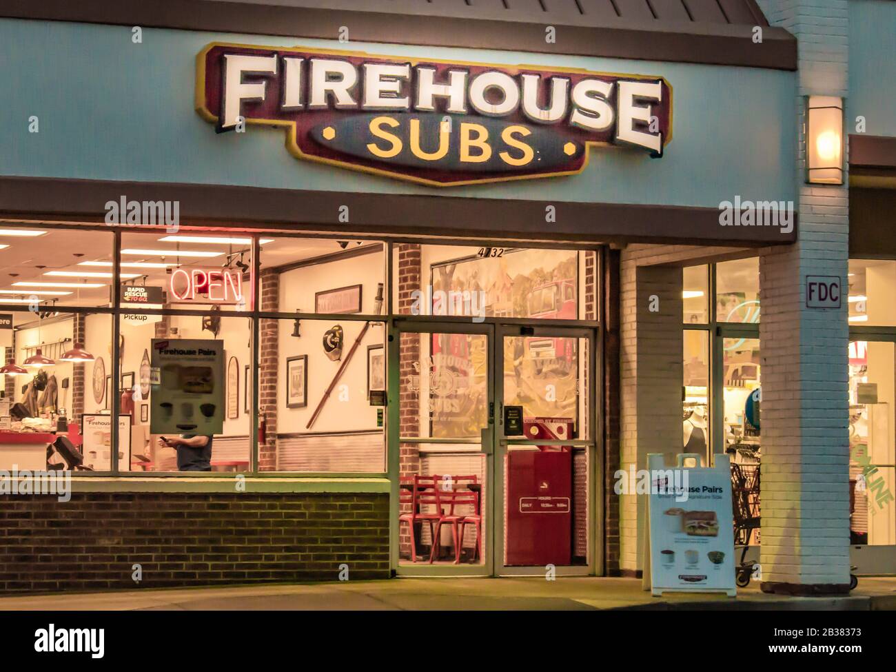Charlotte, NC/USA - 15. November 2019: Horizontaler Schuss von "Firehouse Subs"-Sandwich-Shop mit Marke/Logo mit leuchtem Schild und hell leuchtender Innenausstattung. Stockfoto
