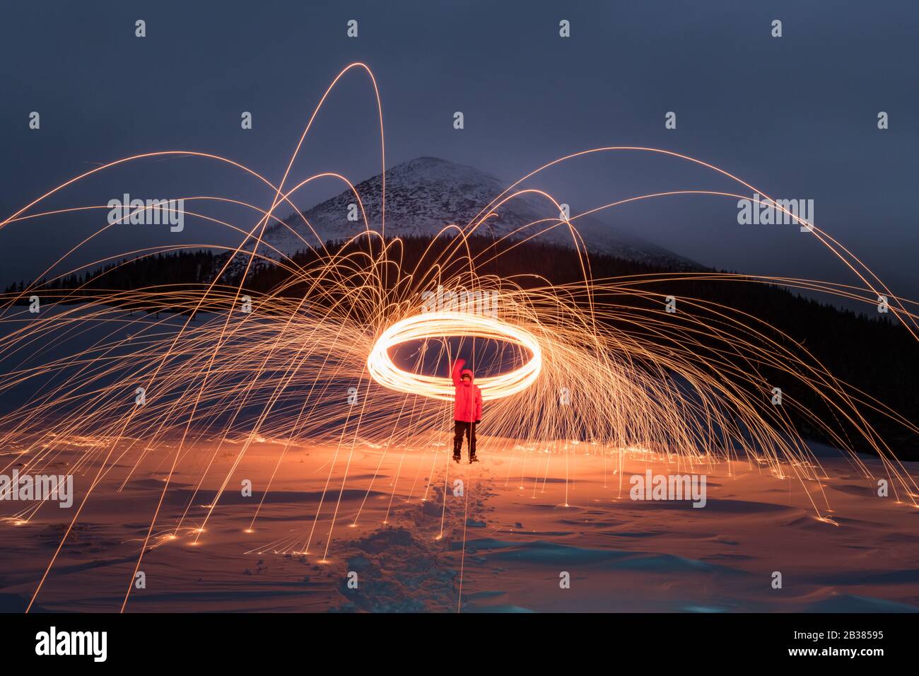 Feuershow mit viel Funken in den Winterbergen der Nacht. Landschaftsfotografie Stockfoto