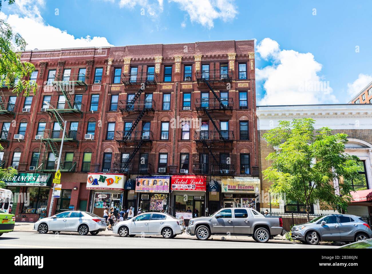 New York City, USA - 4. August 2018: Straße mit alten typischen Apartmentgebäuden mit Brandentzug und Menschen im Harlem Viertel in Stockfoto