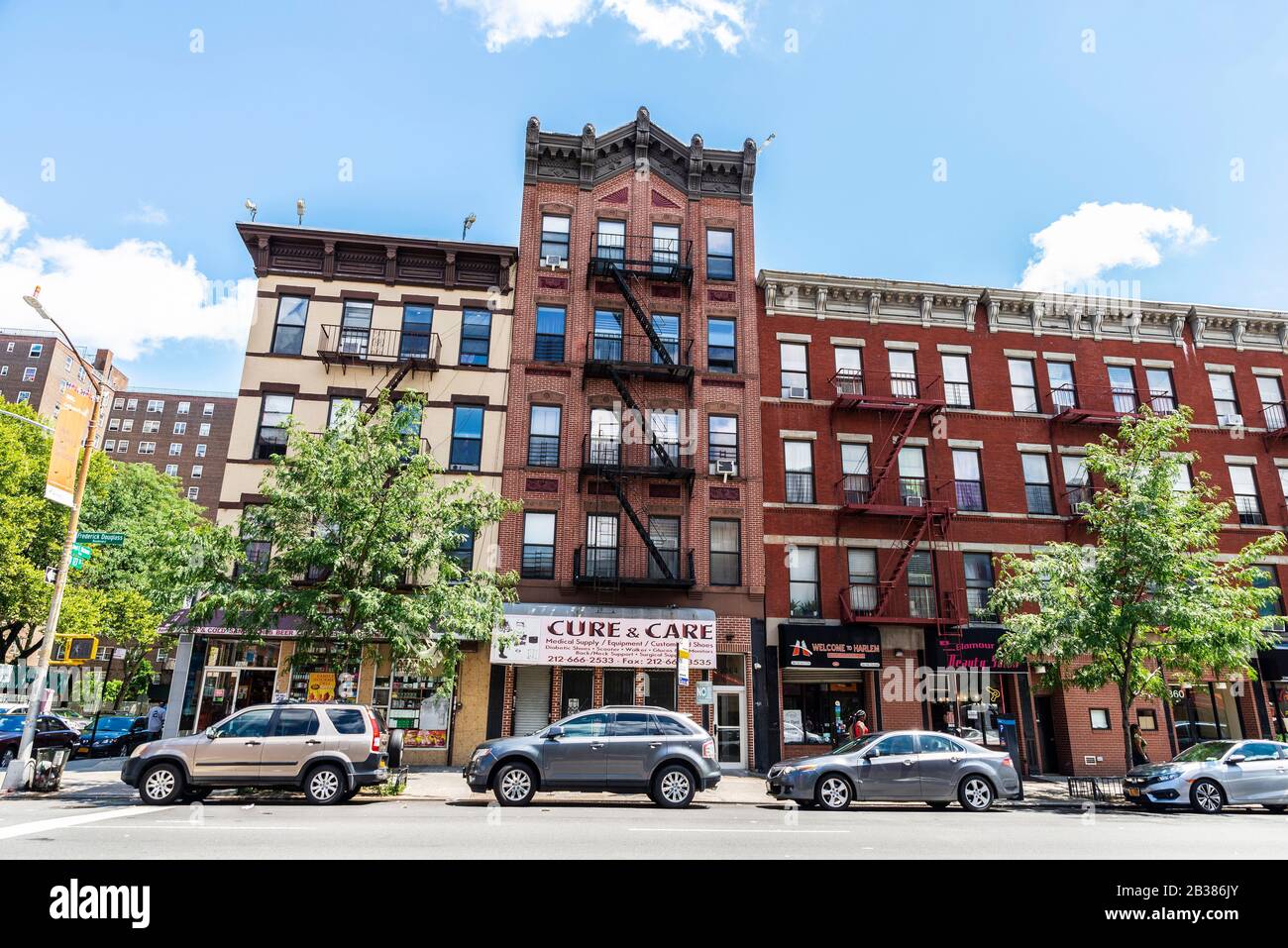 New York City, USA - 4. August 2018: Straße mit alten typischen Apartmentgebäuden mit Brandentzug und Menschen im Harlem Viertel in Stockfoto