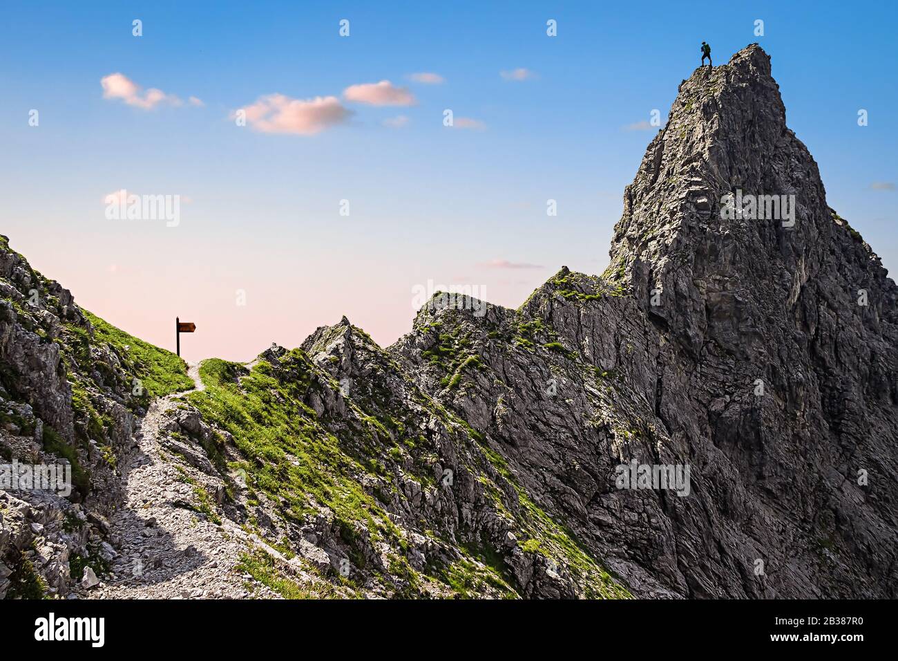 Ein einziger Kletterer auf einem Berggipfel und der Steile Weg zum Gipfel Stockfoto