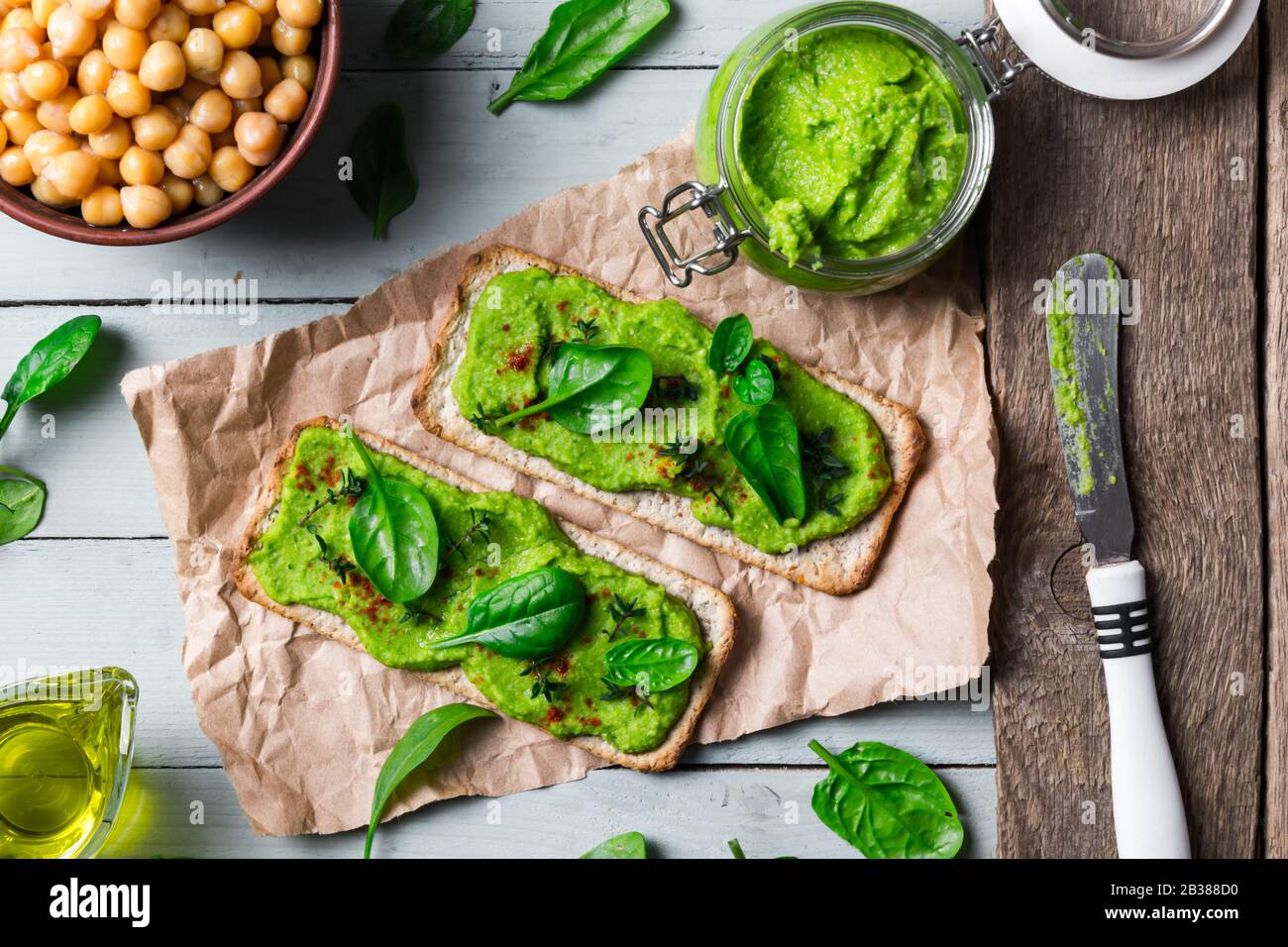 Zwei Kräcker mit grünem Spinathumus auf Holztisch. Flaches Lay. Hummus-Konzept. Lebensmittelfotografie Stockfoto