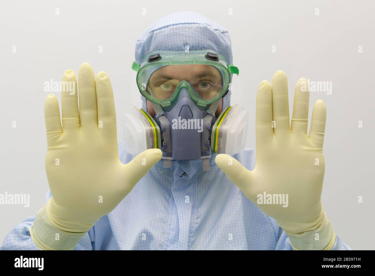 Ein Laboringenieur, der eine spezielle Uniform und Schutzkleidung trägt Gläser und Gesichtsmaske gegen chemisches Gift zeigen Geste durch Handzeichen STOP Stockfoto