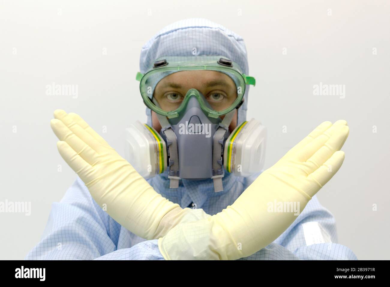 Ein Laboringenieur, der eine spezielle Uniform und Schutzkleidung trägt Gläser und Gesichtsmaske gegen chemisches Gift zeigen Geste durch Handzeichen STOP Stockfoto