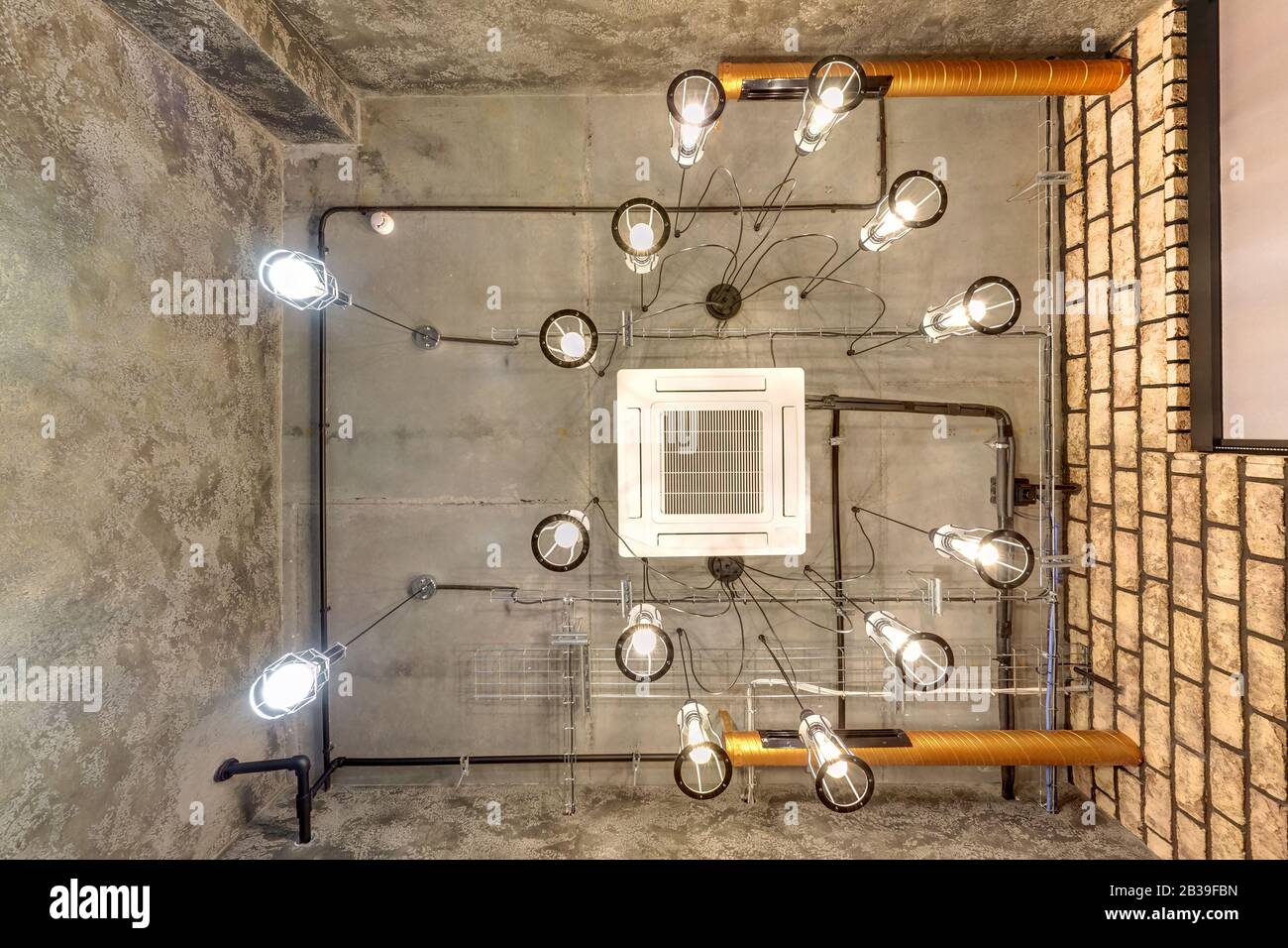Blick auf die graue Betondecke mit Halogenflecken und edison Lampen im  Loft-Büroraum mit Klimaanlage und orangefarbenem Belüftungsrohr, sieht aus  Stockfotografie - Alamy