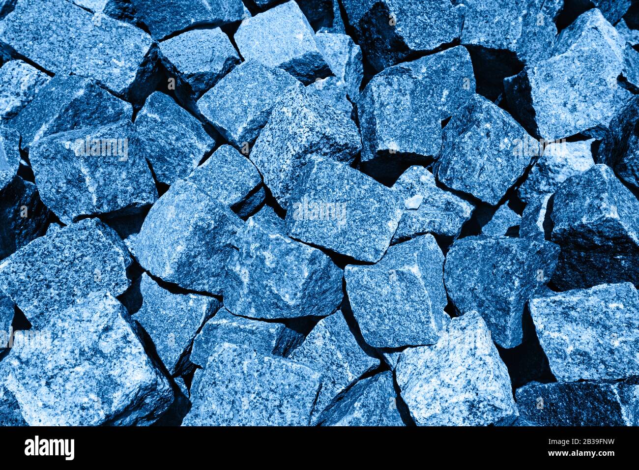 Haufen alter abgenutzter Kopfsteinpflaster. Hintergrund. Farbe des Jahres 2020 klassisch blau getönt. Stockfoto