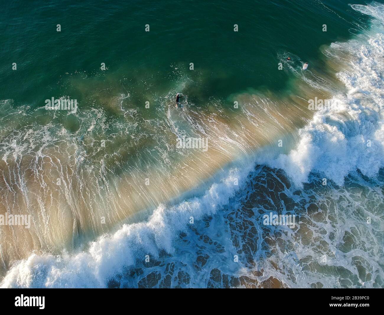 Drone Blick auf schöne türkisblauen Wellen brechen auf sandigen Küste. Luftaufnahme von goldenem Strand, tiefblauem Meerwasser und schäumenden Wellen Stockfoto