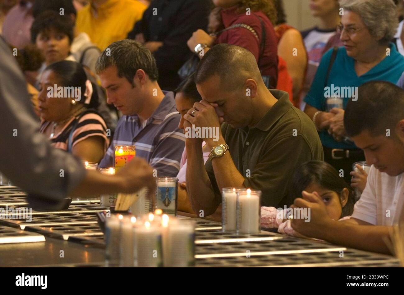 San Juan Texas USA, um 2004: Trauernde knien und beten vor einer Reihe von Votivkerzen in der Basilika unserer Lieben Frau von Del Valle. ©Bob Daemmrich Stockfoto