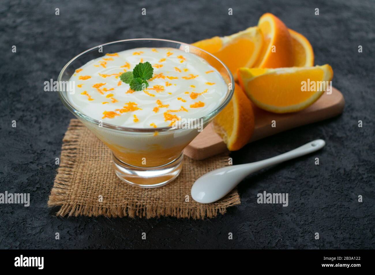 Joghurt mit orangefarbenen und frischen Orangen auf schwarzem Hintergrund. Stockfoto
