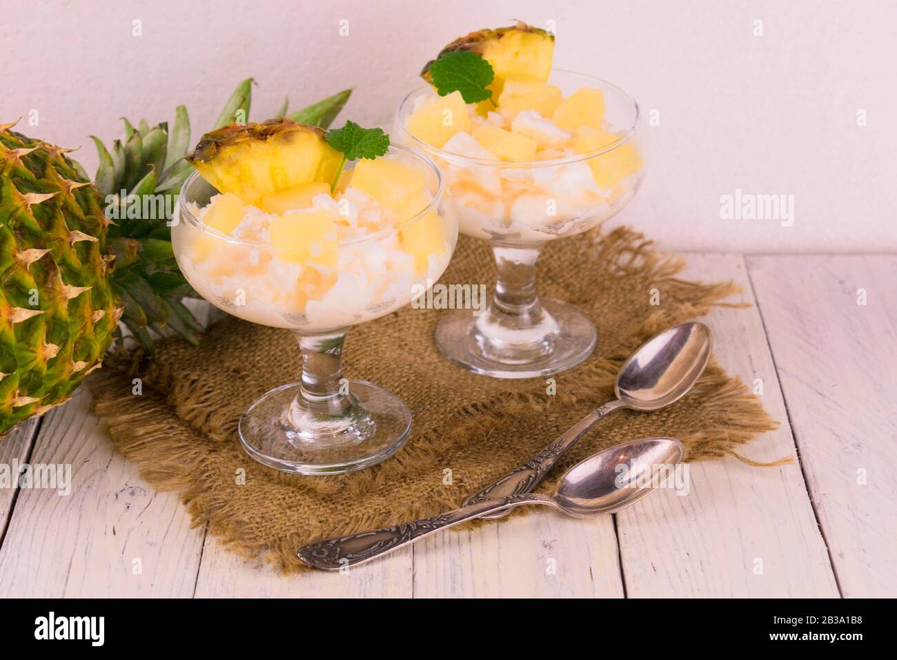 Zwei Portionen tiefgefrorenen Joghurt mit Ananas auf weißem Holzhintergrund. Stockfoto