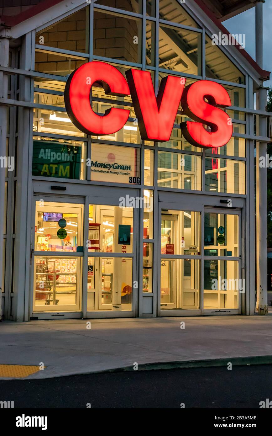 Charlotte, NC/USA - 10. Mai 2019: Glasfassade und Eingang zur "CVS Pharmacy", die hell erleuchtete große Markenbriefe in rot-beleuchtetem Innenraum zeigen. Stockfoto