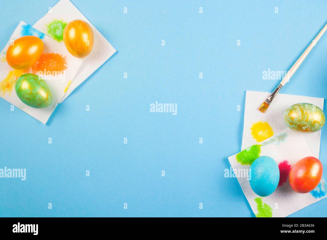 Nur bemalte Eier von Rakhblüten mit einem Gold, das auf Servietten neben einem Pinsel auf blauem Grund trocken stäubt. Kopierbereich. Stockfoto