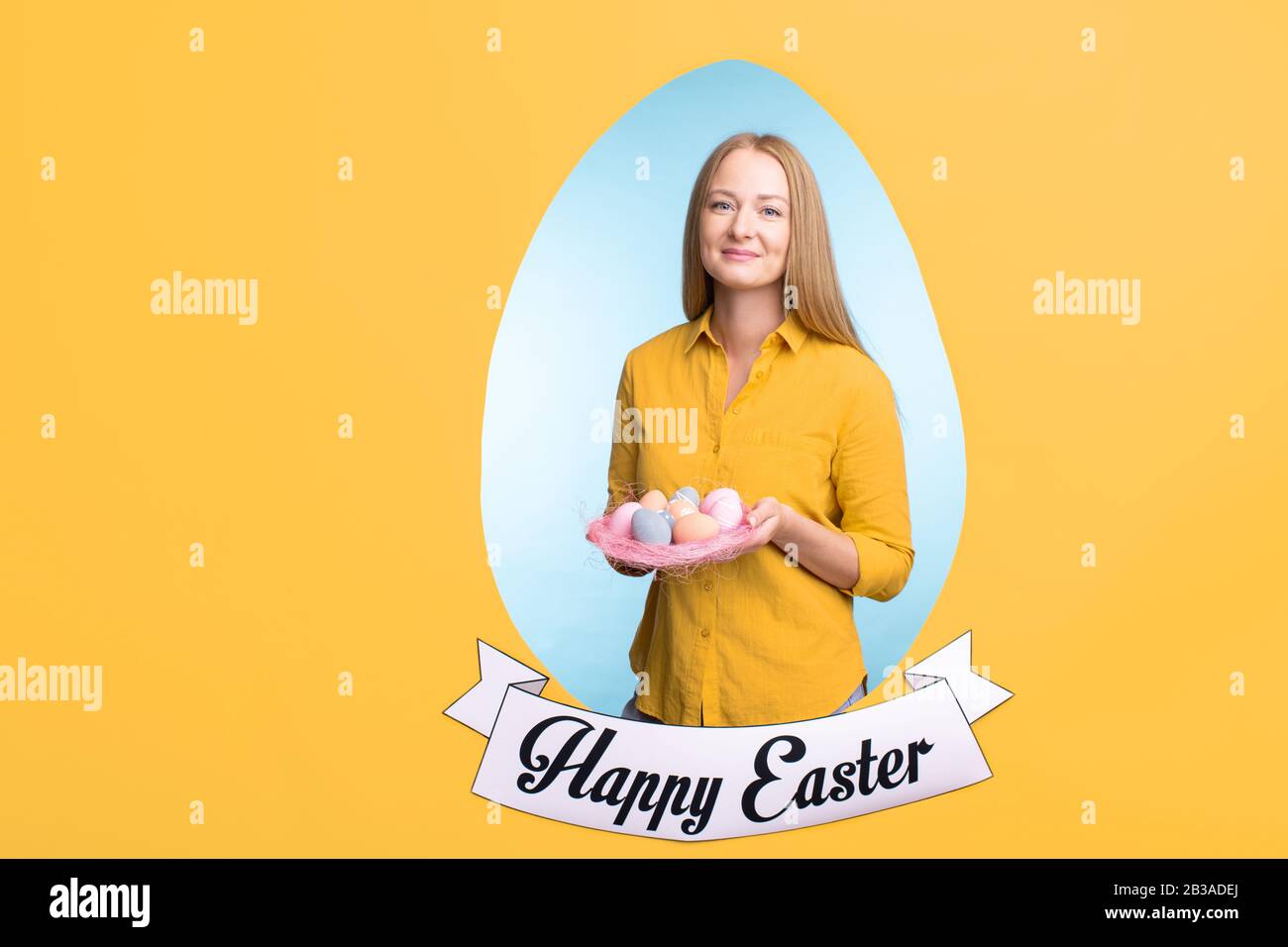 Porträt einer lächelnden jungen blondhaarigen Frau, die mit Ostereiern in eiförmigem Rahmen posiert Stockfoto