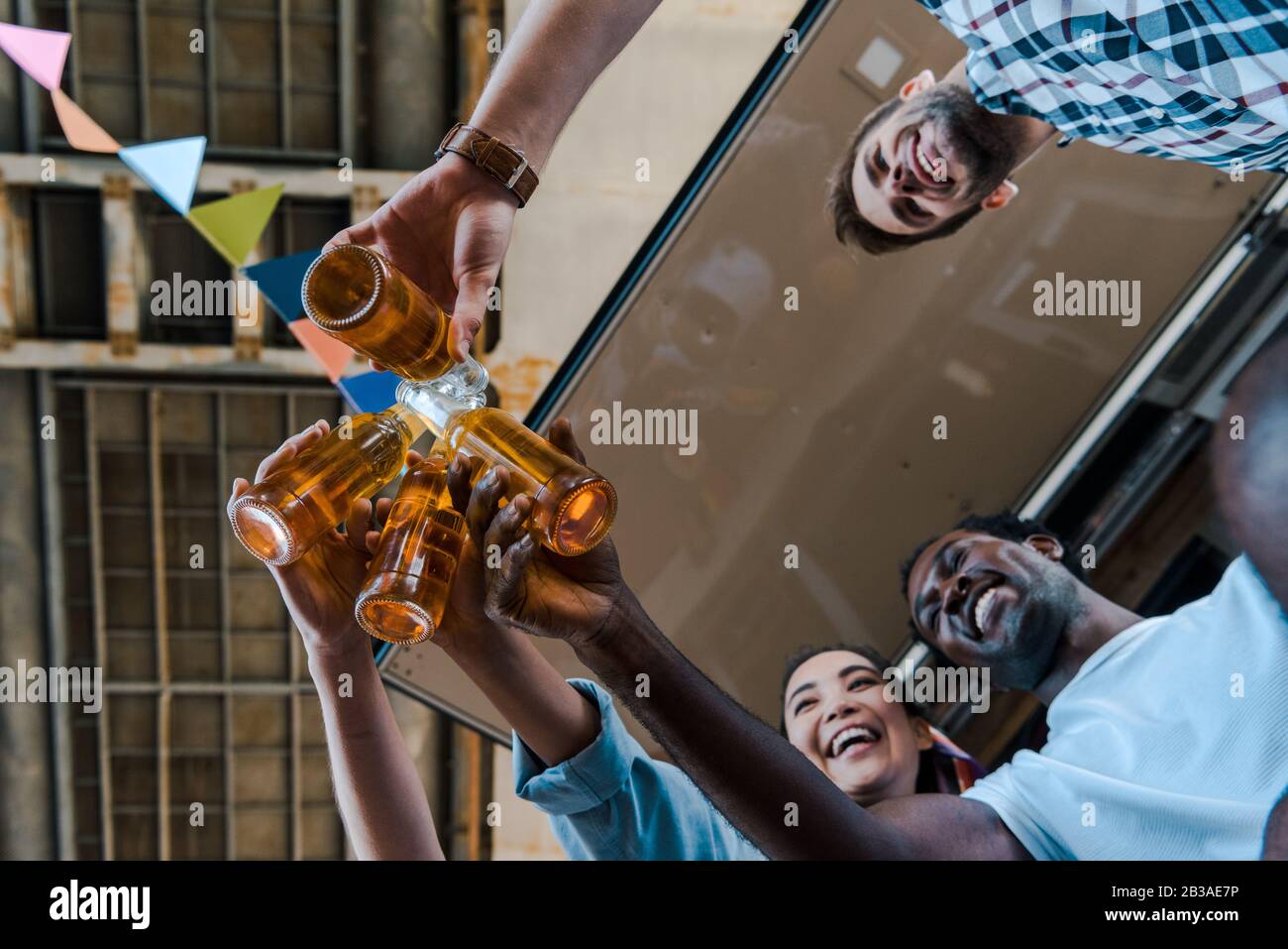 Die untere Ansicht der glücklichen multikulturellen Freunde, die Flaschen mit Bier toben Stockfoto