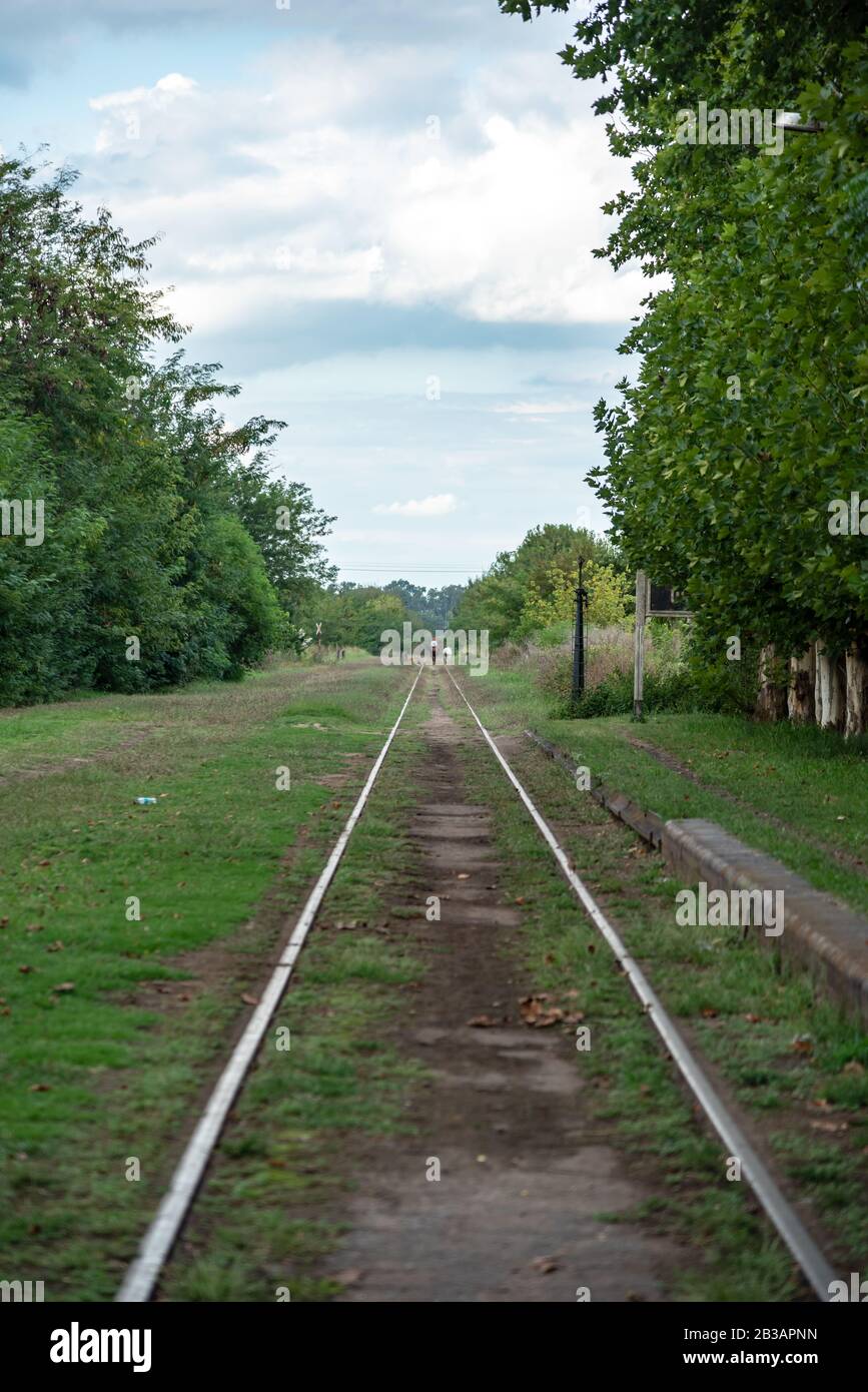 Eine verlassene Bahntrasse, umgeben von Pflanzen mit einer Person auf einem Pferd ganz hinten Stockfoto