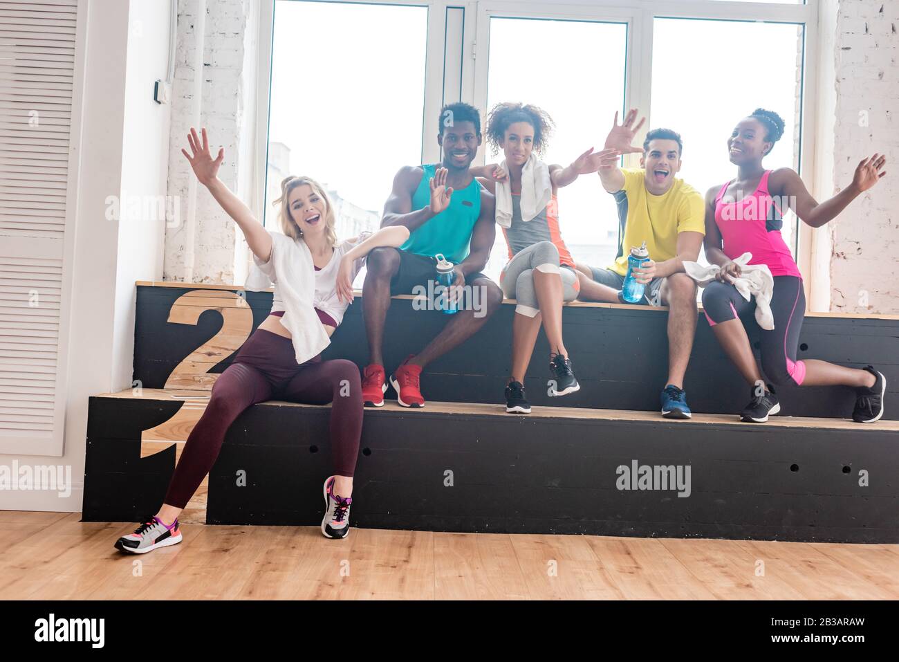 Lächelnde multiethnische zumba-tänzerinnen grüßen in der Kamera im Tanzstudio Stockfoto