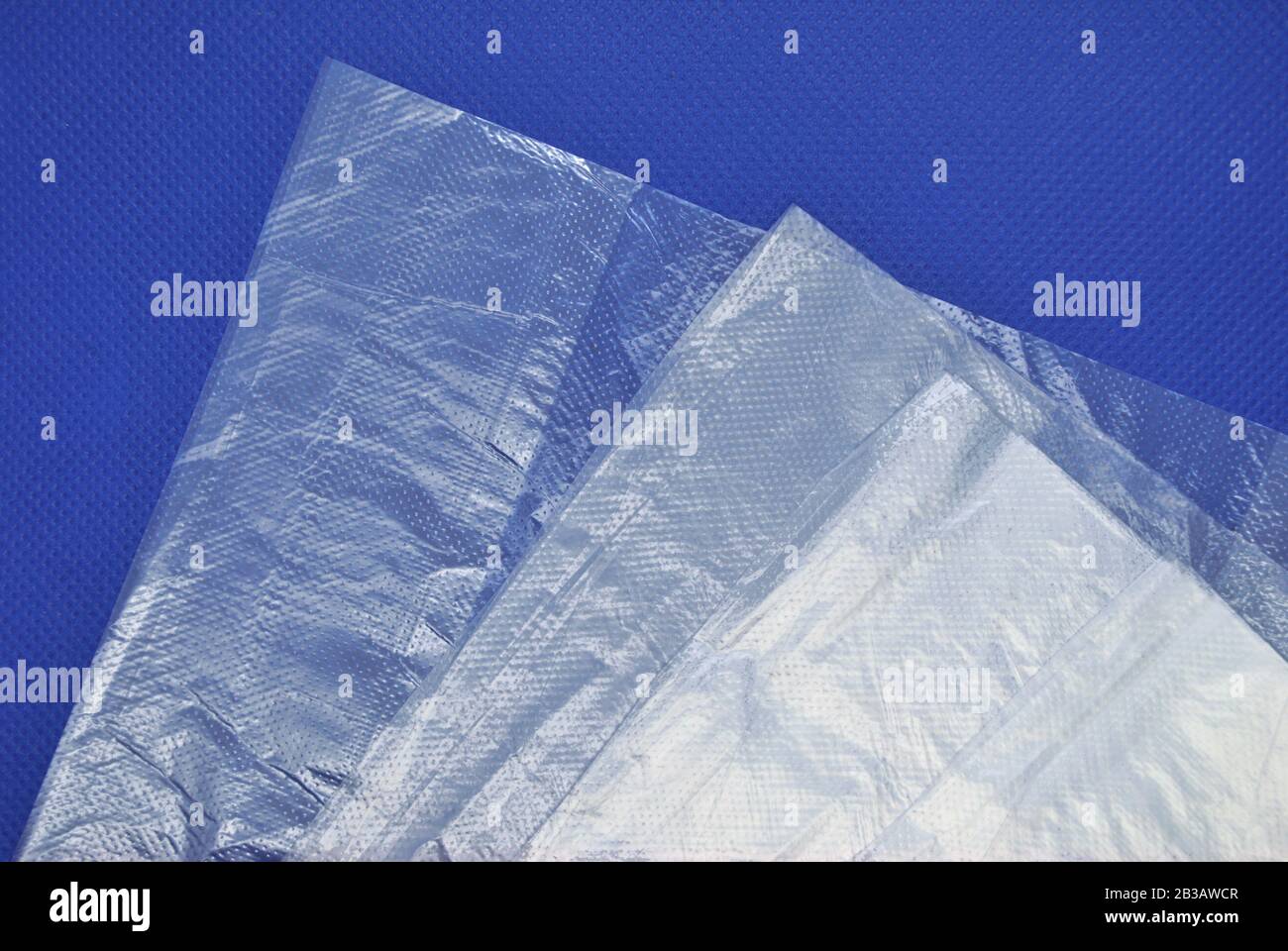 Gefaltete neue, einfarbige, transparente Kunststoffbeutel aus Polyethylen aus dem Supermarkt auf blauem Hintergrund Stockfoto