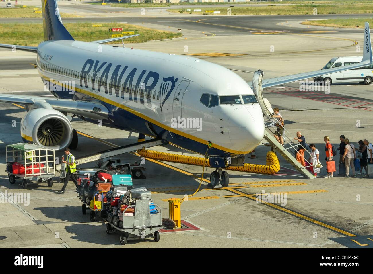 Neapel, Italien - AUGUST 2019: Fluggäste eine Ryanair Boeing 737 Jet am Flughafen Neapel. Das Gepäck wird von Gepäckwagen geladen Stockfoto