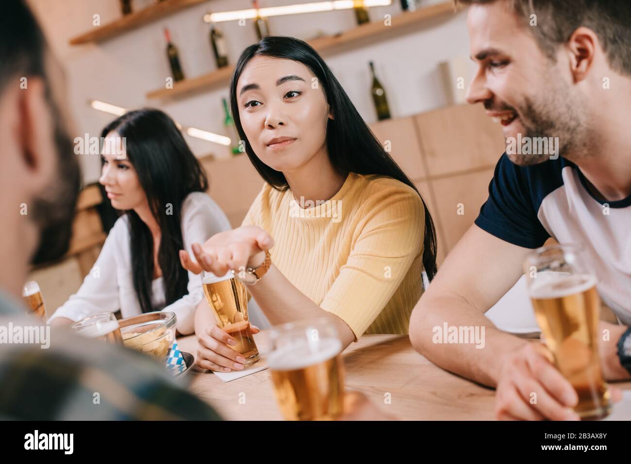 Selektiver Fokus der jungen asianerin, die im Pub mit Freunden sitzt Stockfoto