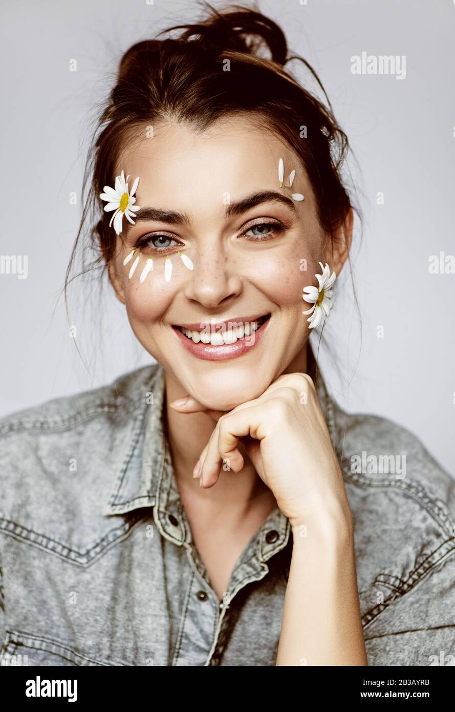 Schöne junge Frau mit Blumen im Gesicht. Federkonzept. Stockfoto