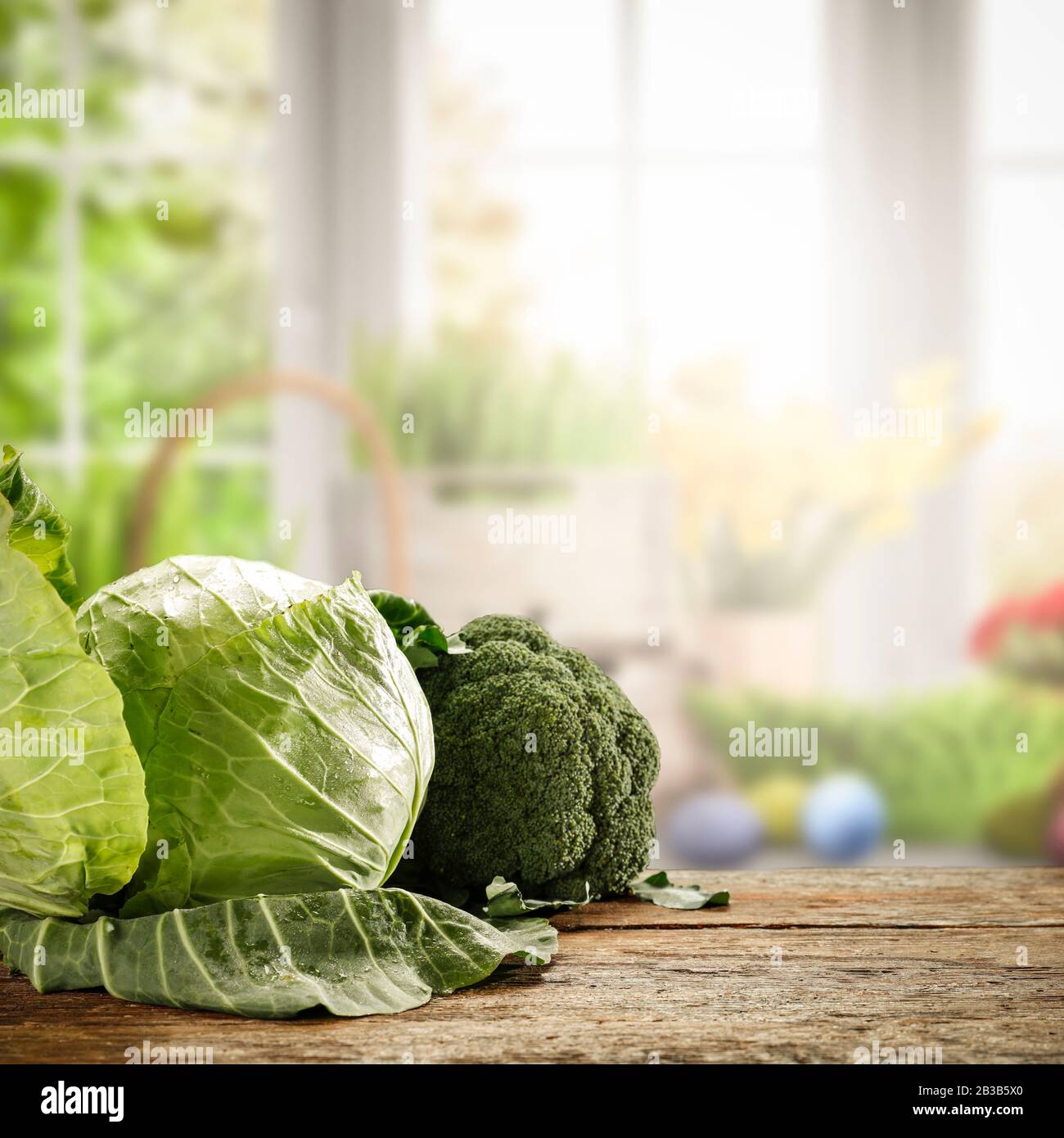 Frühlingszeit und frisches Gemüse mit Holztisch mit idyllischem ländlichen Bildhintergrund vor dem Fenster. Stockfoto