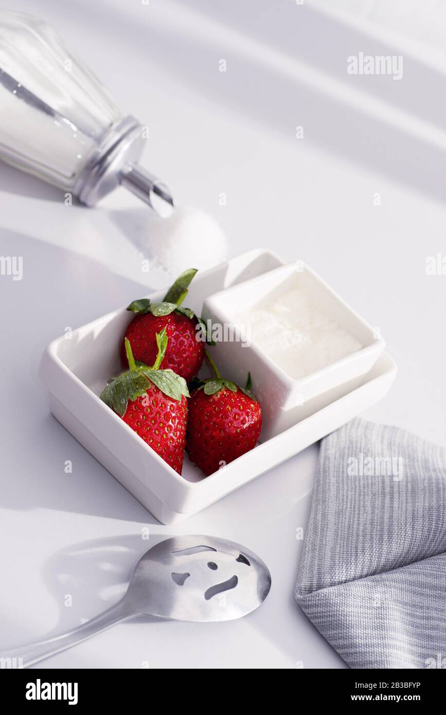 Frische Erdbeeren und Creme in eckigen weißen Schüsseln Stockfoto