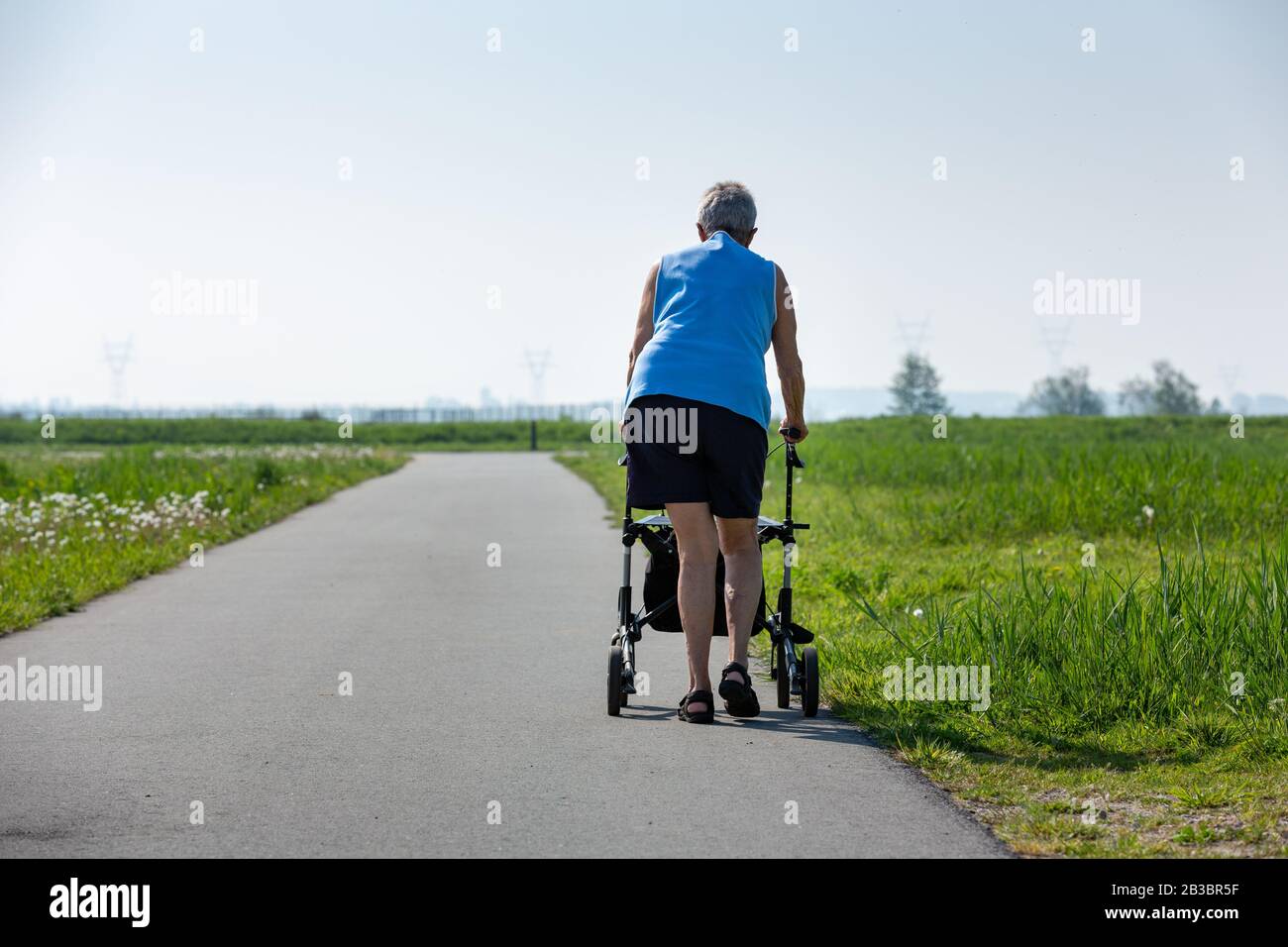 Eine ältere Frau mit einem Geher, die ihr hilft, in der Natur zu Fuß nach draußen zu gehen. Leiderdorp, Niederlande. Stockfoto