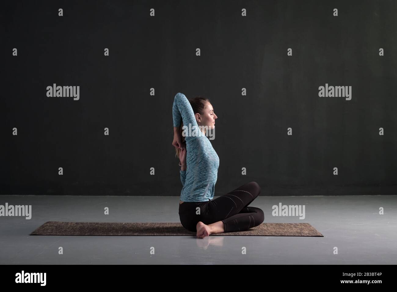 Weiße schöne Frau im Sitzen fortgeschrittene Yoga-Pose, Kuh Gesicht Asana, auf schwarzem Hintergrund Stockfoto