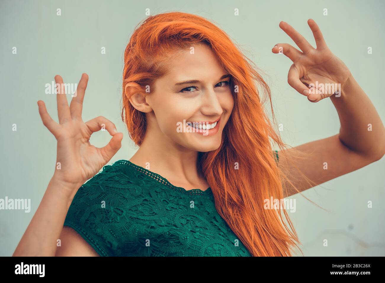 Schöne junge Rotkopffrau Ith langes Ingwerhaar mit Ok-Schild auf Himmelshintergrund. Positive menschliche Emotionen sind Ausdruck Körpersprache Stockfoto