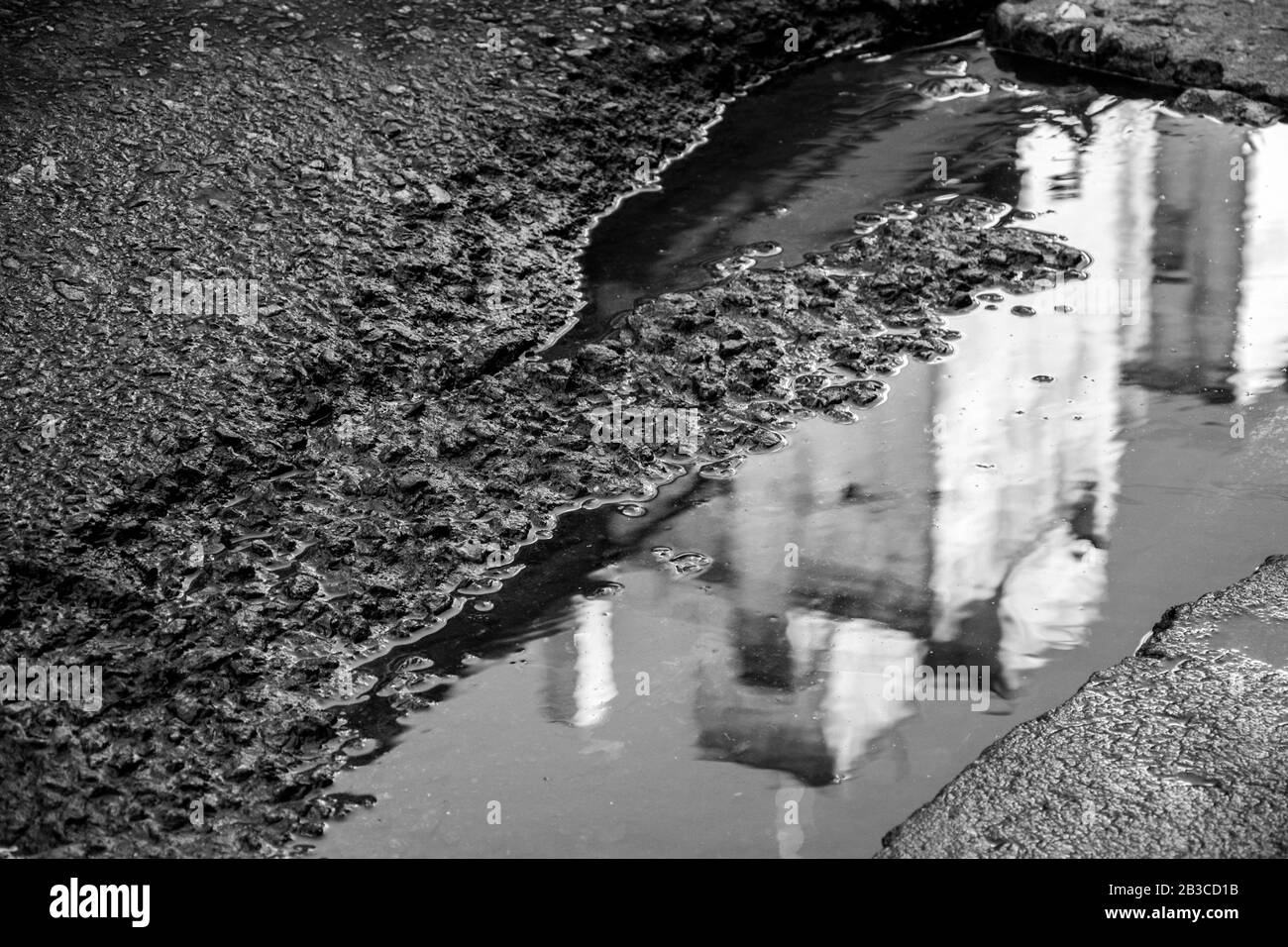 Urbane Reflexion in einer Straßenpfütze Stockfoto