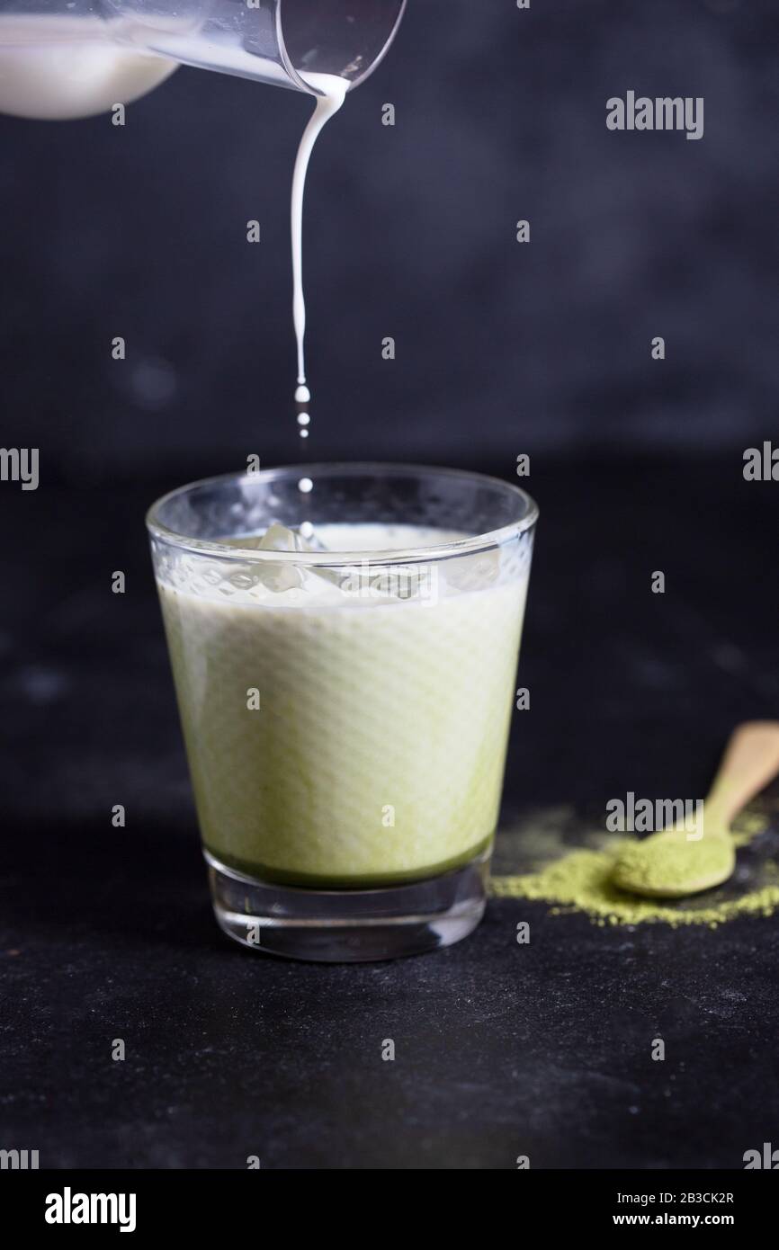 Heiße grüne Matcha Latte mit Mandelmilch auf schwarzem Hintergrund Stockfoto