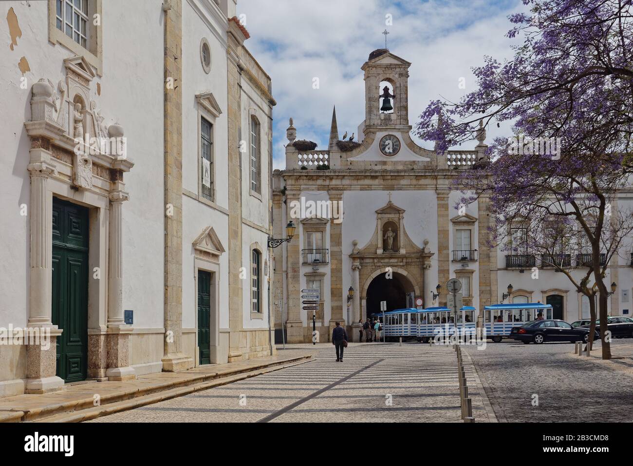 Touristenzug fährt durch den Stadtbogen, Arco da Vila in Faro, Portugal. Der neoklassizistische Torbogen wurde 1812 an der Stelle eines mittelalterlichen Tores erbaut Stockfoto