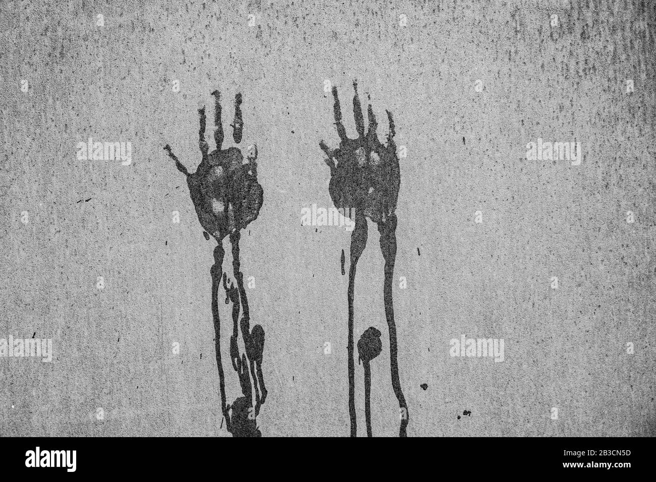 Abdrücke von zwei nassen tropfenden Händen an einer Wand in Schwarzweiß - gruselige Szene mit Kopierbereich Stockfoto