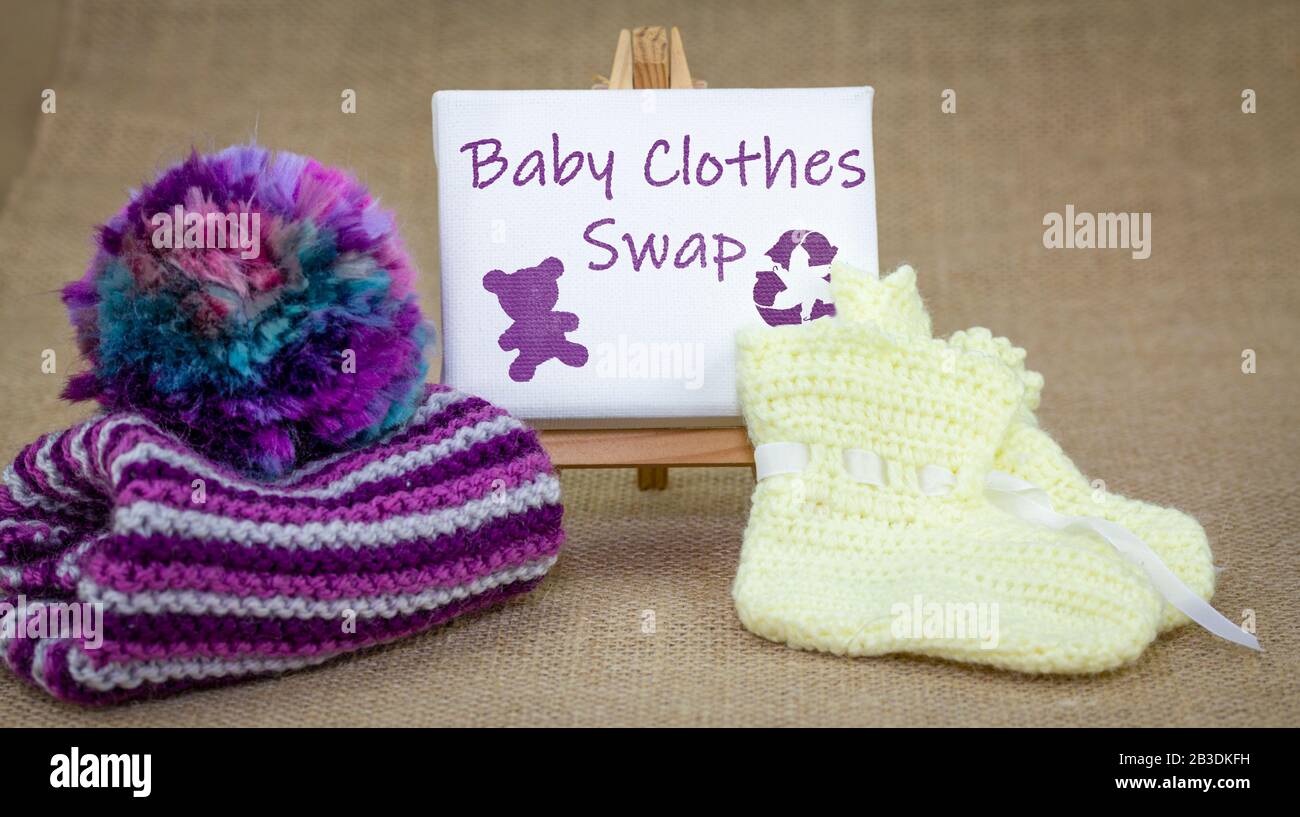 Babybekleidung tauscht Schild und Babykleidung auf Burlap Hintergrund aus, recycelt Baby- und Kinderkleidung und Textilien, nachhaltiges Modekonzept. Stockfoto