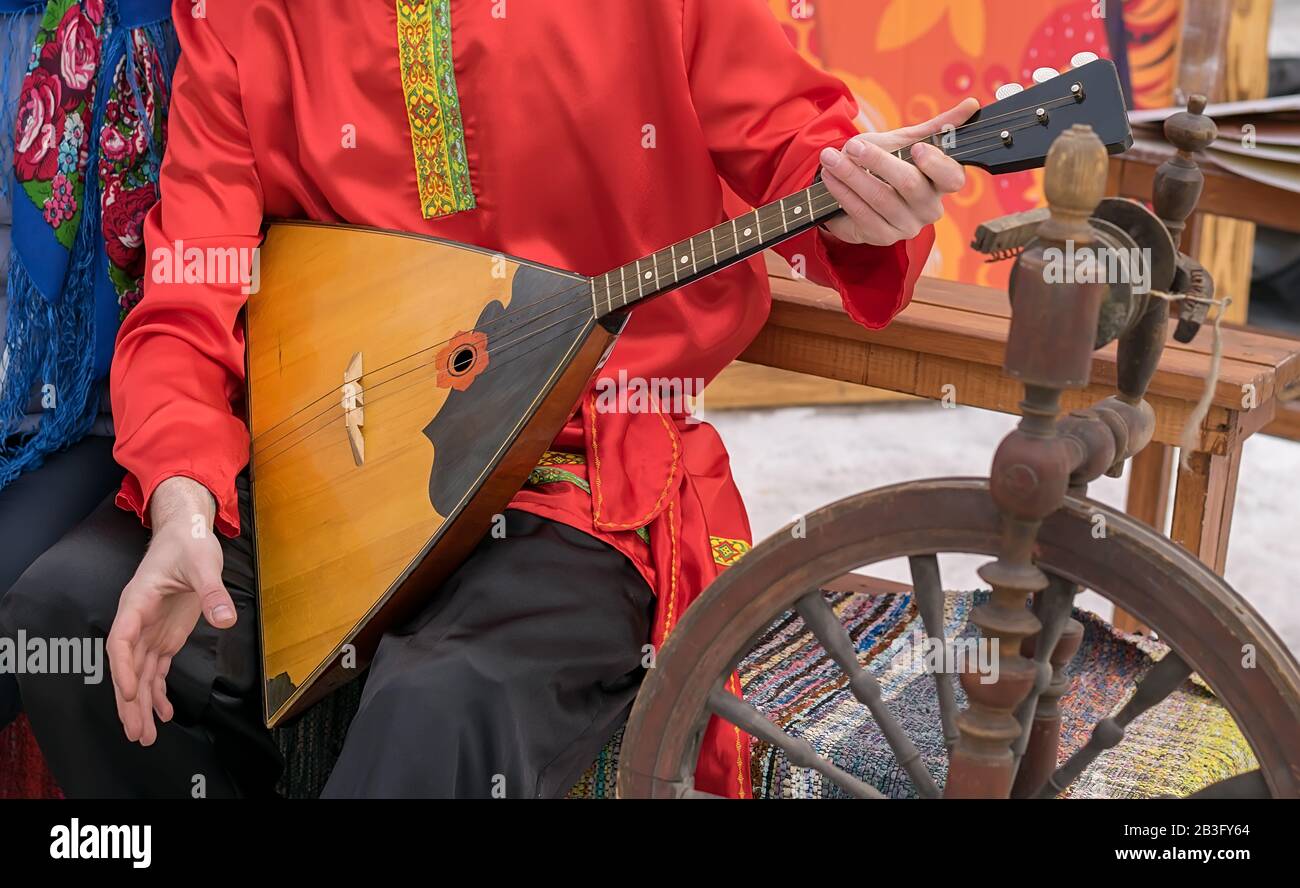 Der Musiker spielt ein russisches Volksmusikinstrument, eine Balalaika, in einem uralten Nationaltracht Stockfoto