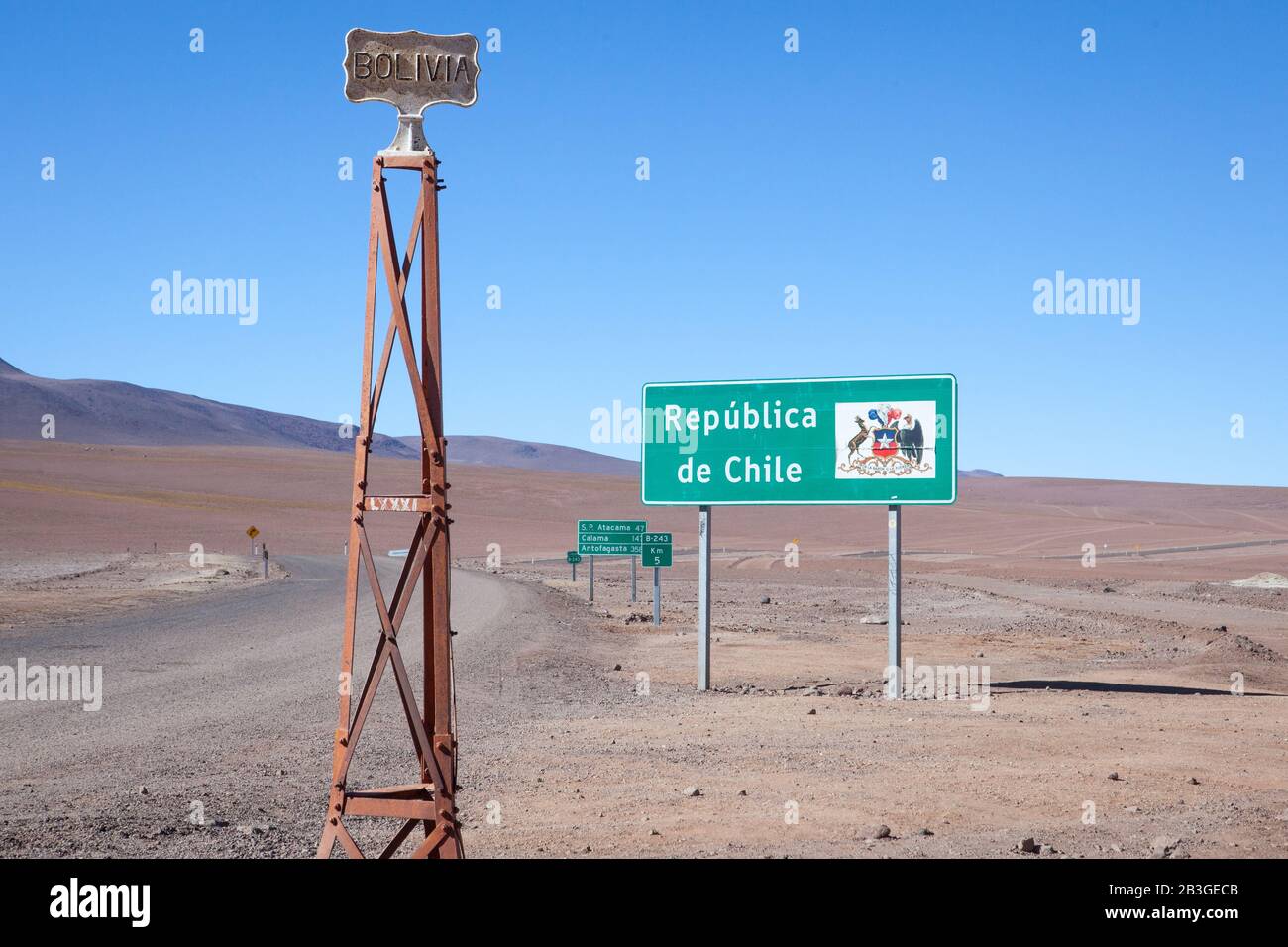 Ein Paar Schilder unterscheiden die Grenze zwischen Bolivien und Chile in der trockenen desolaten Wüste. Stockfoto