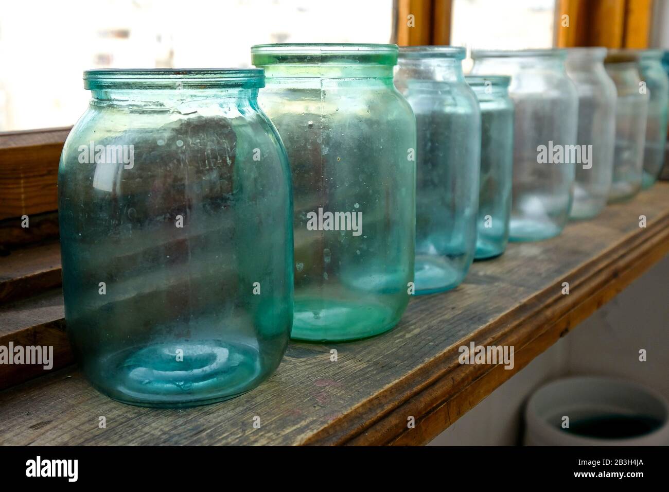 Glasgefäße für die Konservierung befinden sich auf dem Balkon. Schmutzige, nicht vorbereitete Dosen. Liter Dosen für Lagerung Stockfoto