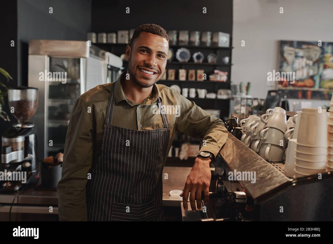 Portrait des jungen afro-amerikanischen männlichen Geschäftsinhabers hinter dem Ladentisch, lächelnd mit Blick auf die Kamera Stockfoto
