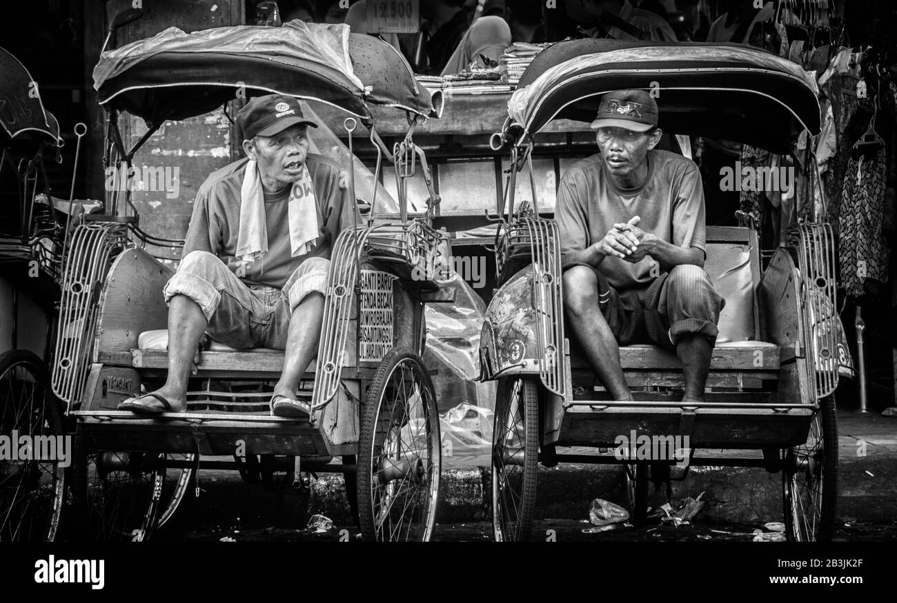 Zwei Rickshaw-Fahrer teilen sich einen Chat über ihre Mittagspause in der geschäftigen Stadt Yogyakarta. Dieses Bild gibt einen Einblick, auch wenn überhaupt so kurz, in t Stockfoto