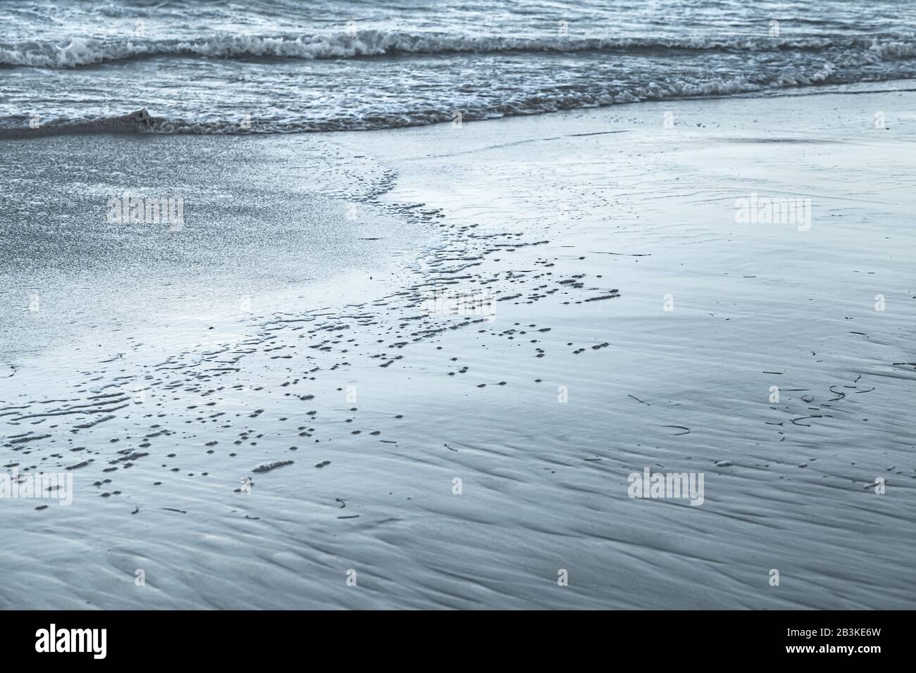 Nasser Sand am Ufer und Meerwasser, natürliches blaues Küsten-Foto Stockfoto