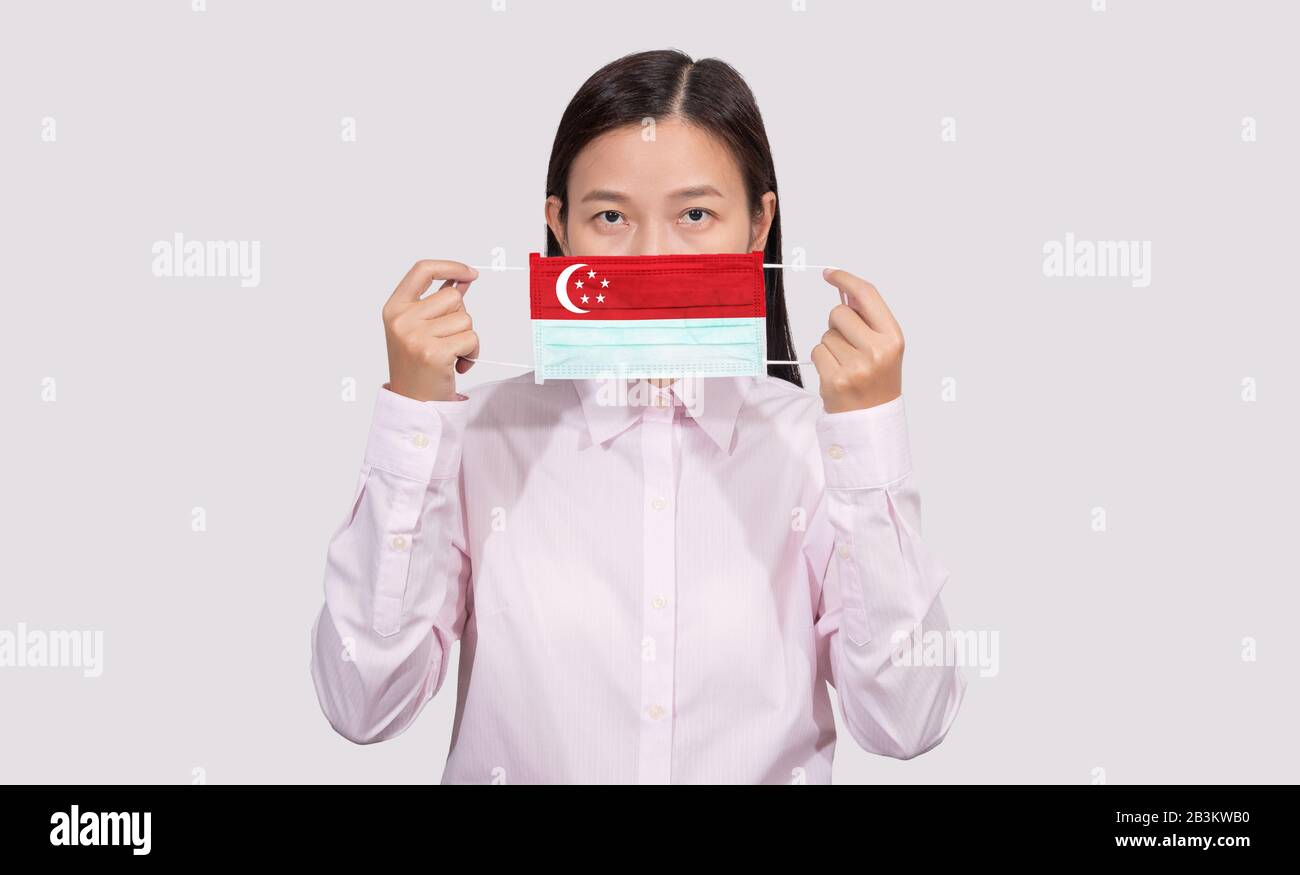 Asiatische Frau, die hygienische Gesichtsmaske trägt, die Singapur-Flagge lackiert, um sich vor dem Coronavirus 2019 (COVID-19) Infektionsausbruch, dem Virus, zu schützen Stockfoto