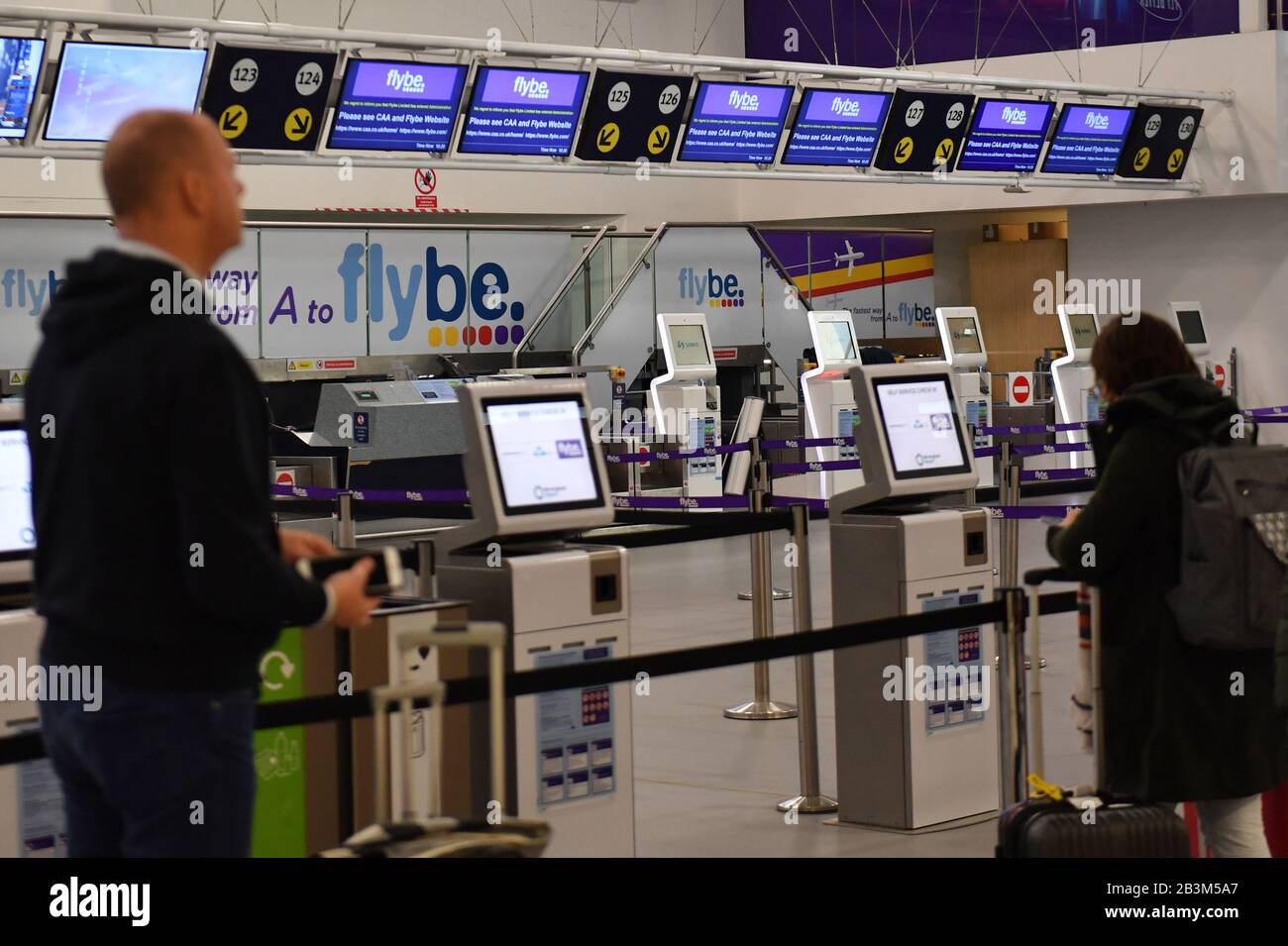 Passagiere stehen an leeren Check-in-Schaltern am internationalen Flughafen Birmingham, da Flybe, Europas größte regionale Fluggesellschaft, in die Verwaltung eingebrochen ist. Stockfoto