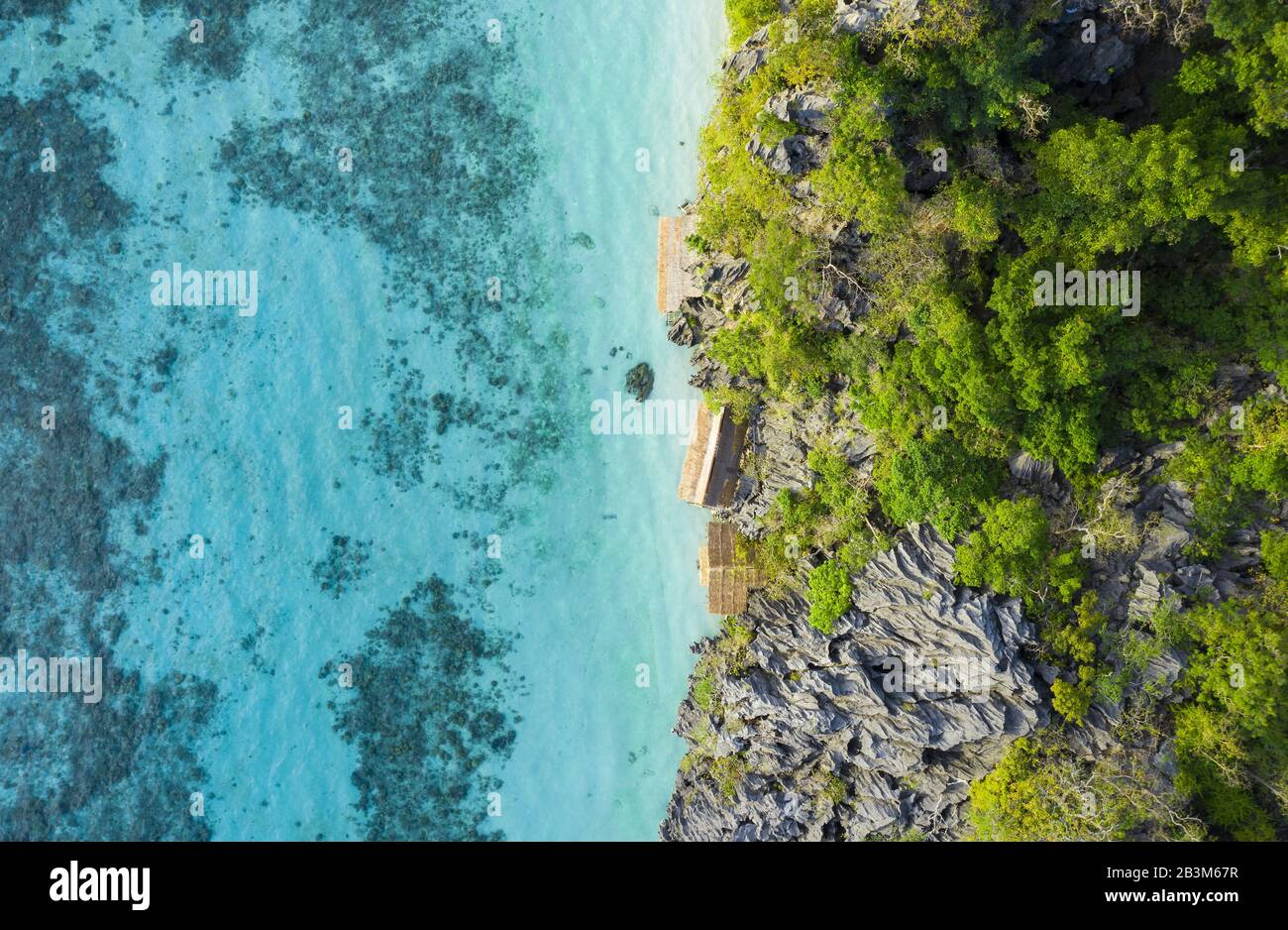 Blick von oben, atemberaubender Luftblick auf einige von felsigen Klippen umgebene, von einem türkisfarbenen, kristallklaren Meer umgebene, Zimmer. Malwawey Coral Garden. Stockfoto