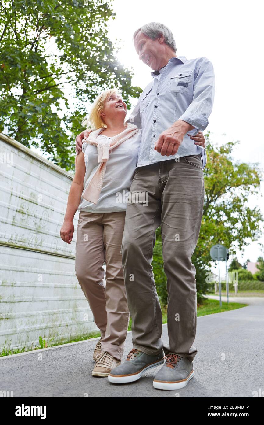 Ein paar Senioren gehen im Sommer gemeinsam in der Stadt spazieren Stockfoto
