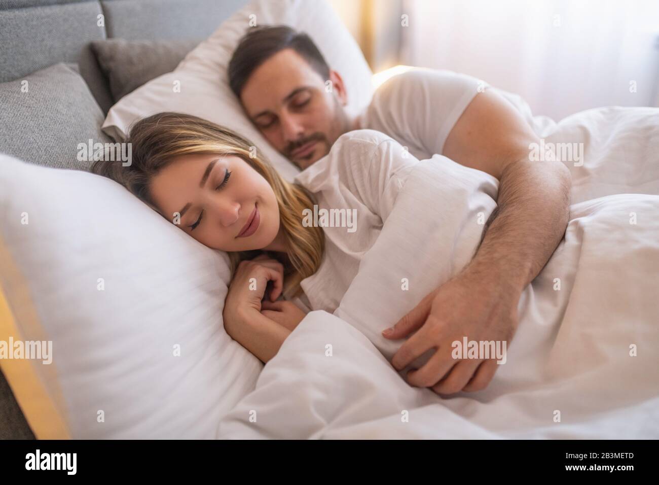 Glückliches Paar, das zu Hause im Bett schläft.Kleines süßes Paar, das im Bett schläft.Romantische Momente. Stockfoto