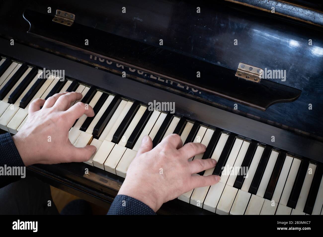Hände, die das alte schwarze Klavier spielen Stockfoto