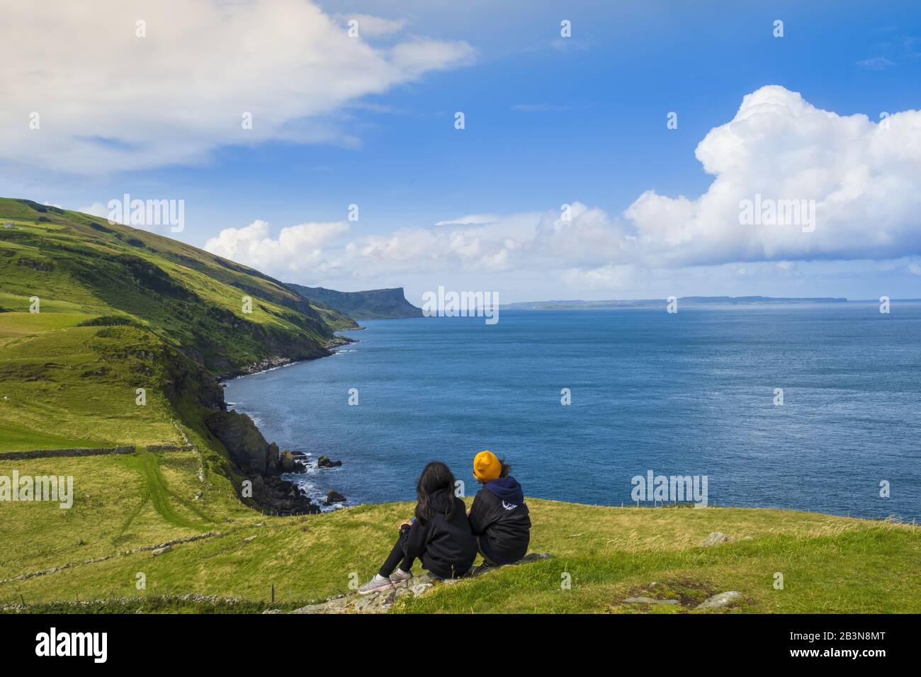 Zwei junge Wanderer, die sich auf einem Wanderweg entlang der Küste von Antrim, Ulster, Nordirland, Großbritannien und Europa ausruhen Stockfoto